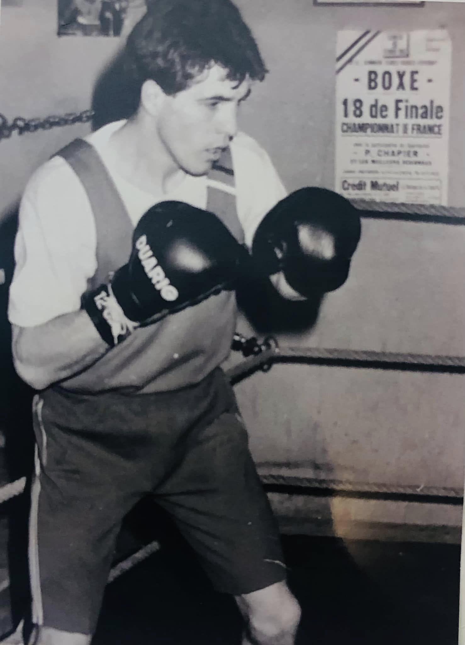 Jeune boxeur en action, affiche du Championnat de France visible au mur